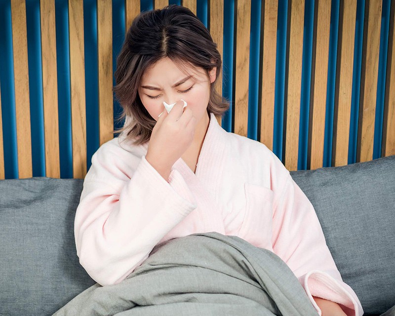 A sneezing woman sitting in a bed